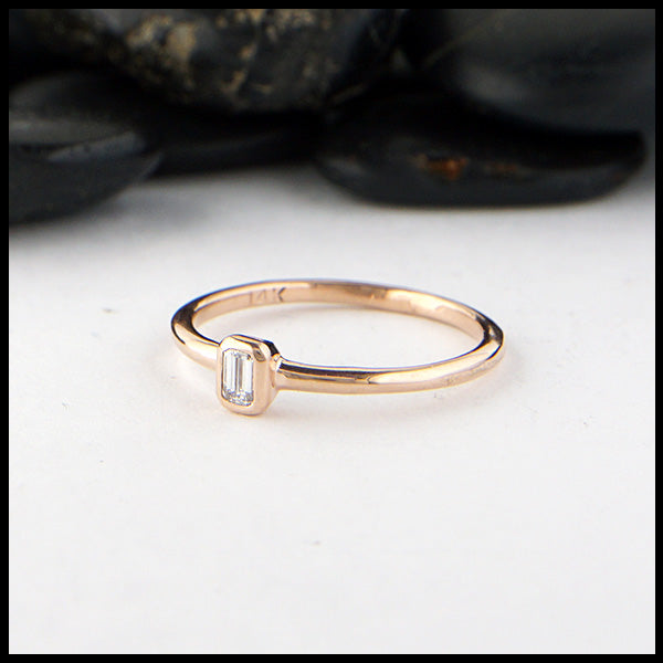 Simple 14K Rose Gold ring bezel set with a 0.09ct Emerald Cut Diamond.