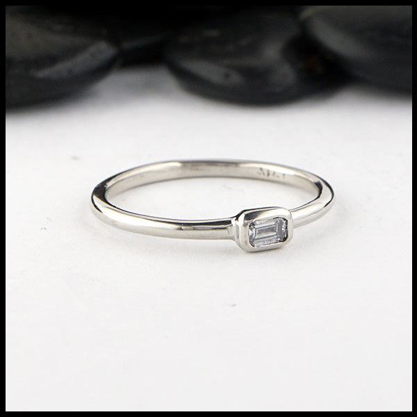 Simple 14K White Gold ring bezel set with a 0.09ct Emerald Cut Diamond.