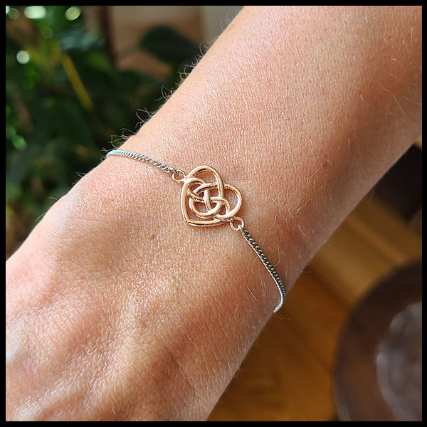Robin's Heart bracelet features a 14K Rose gold heart on a 14K white gold chain. The Heart intertwines with an eternity knot in the center symbolizing eternal love. 
